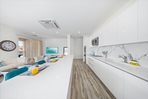 Una cocina moderna con armarios blancos, salpicadero de mármol y microondas integrado.