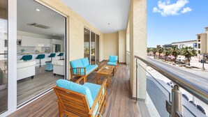 A balcony with wooden furniture and a view of a street and buildings. - Lux Palm Beach Escape Pool Gym Prime Location (Noord)