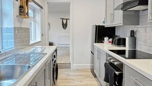 A modern kitchen with a dishwasher, oven, and a window above the sink.