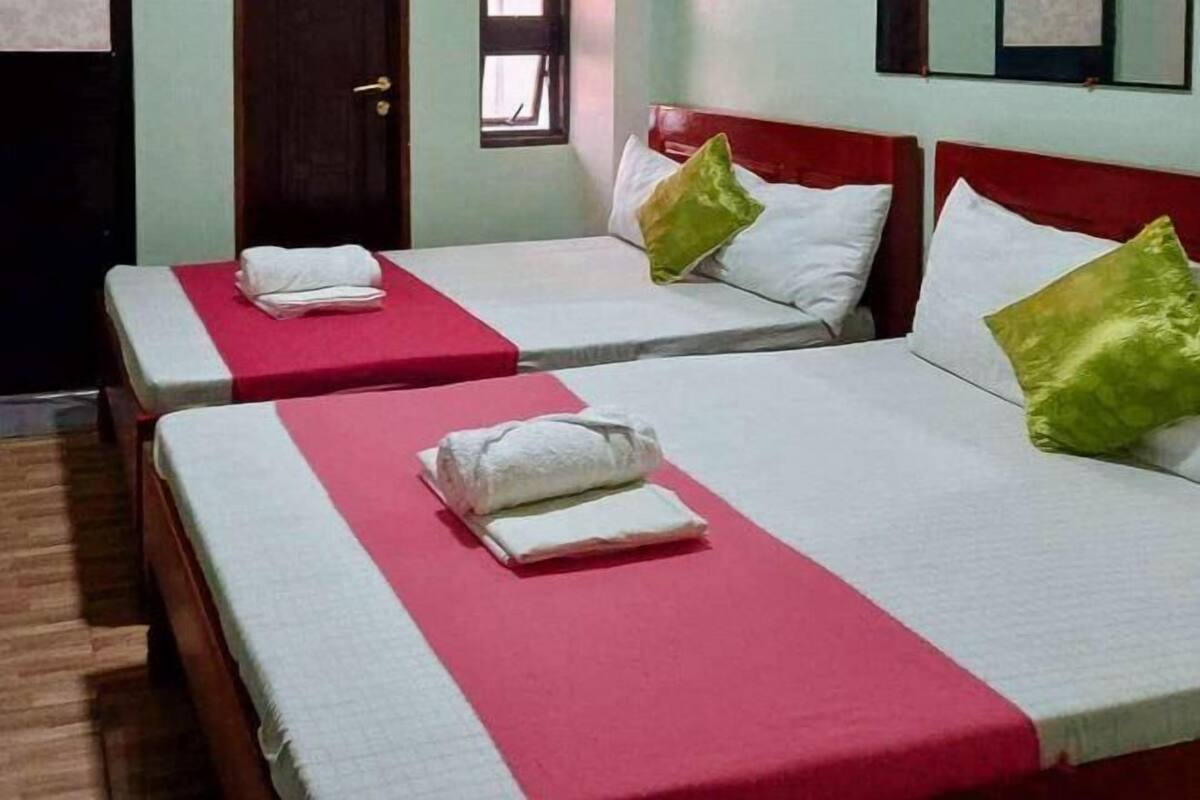 A hotel room with two beds, each with a red and white bedspread, pillows, and neatly folded towels.