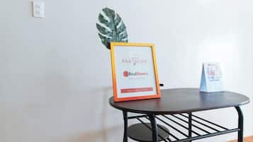 A small table with a framed sign, a potted plant, and a small stand with a card.