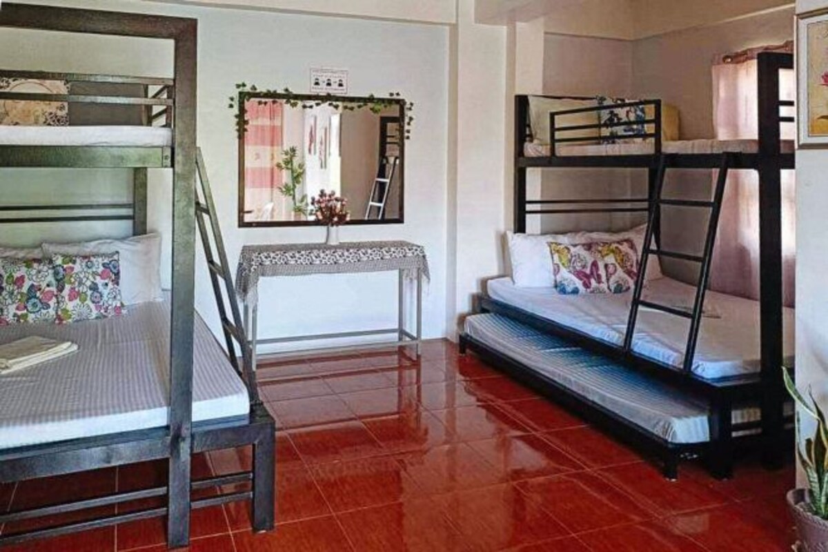 Una habitación tipo dormitorio con literas, un escritorio pequeño y un espejo.