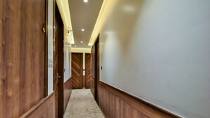 A hallway with wooden paneling, a marble floor, and recessed lighting. - HOTEL RV GOLDEN (Amritsar)