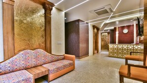A modern lobby with a sofa, wooden columns, and a patterned wall. - HOTEL RV GOLDEN (Amritsar)