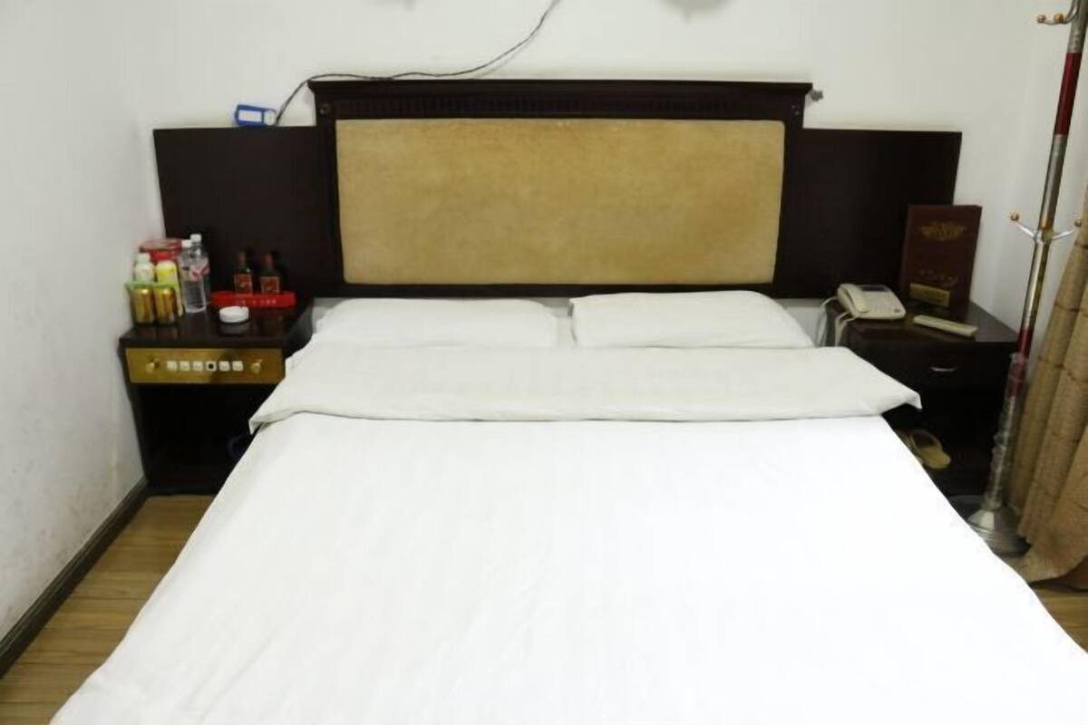 Een hotelkamer met een bed, een nachtkastje met een telefoon en een kleine tafel met flessen.