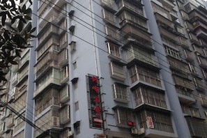 Un edificio de varios pisos con balcones y un letrero vertical con letras rojas.
