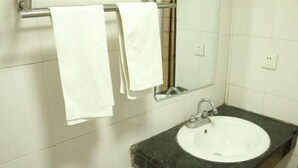 A bathroom with a white sink, a mirror, and two towels hanging on a metal towel rack.