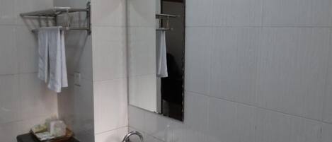 Un baño con un lavamanos blanco, un espejo y un perchero para toallas.