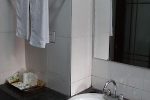 Un baño con lavamanos, espejo y toallero.