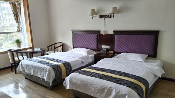 A hotel room with two beds, a desk, and a window.