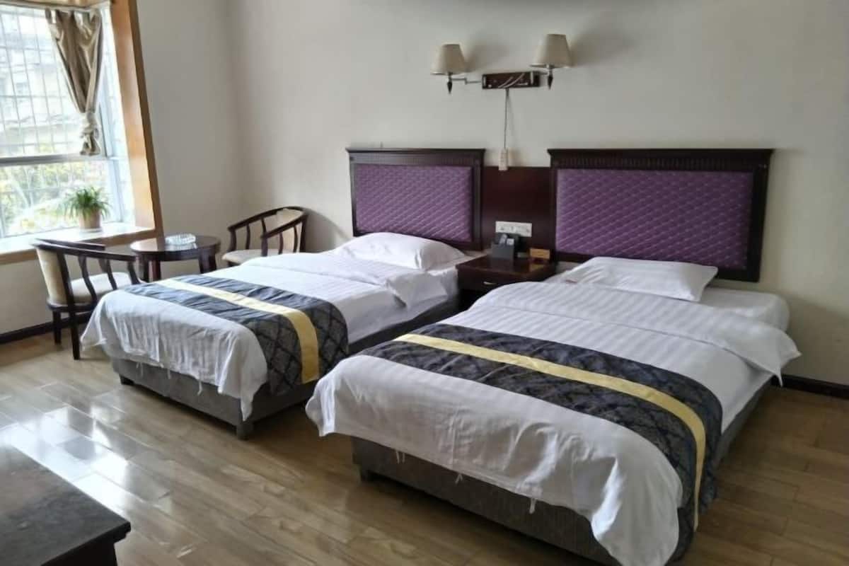 Een hotelkamer met twee bedden, een bureau en een raam.