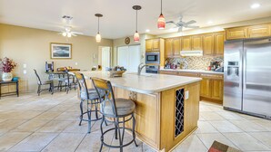 A spacious kitchen with a large island, wooden cabinets, stainless steel appliances, and pendant lighting. - Near Surprise Stadium! Home w/ Pet-Friendly Yard (Sun City West)
