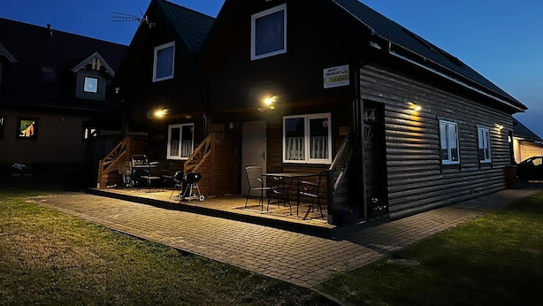 A log cabin with a covered patio, outdoor seating, and a visible staircase leading to the entrance.