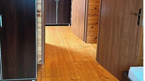 A wooden-paneled room with a wardrobe, a bed, and a door leading to another room.