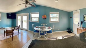 A spacious living area with a sofa, chairs, a dining table, and a kitchen with a sink and countertop.