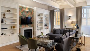 A modern living room with a fireplace, a sofa, a coffee table, and a TV. - Bargello Penthouse By Geco Vacation Rentals (Florence)