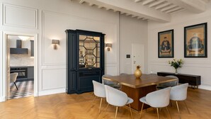 A dining area with a wooden table, four chairs, a black cabinet, and wall-mounted lamps. - Bargello Penthouse By Geco Vacation Rentals (Florence)