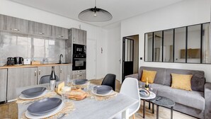 Et moderne køkken med lysegrå skabe, et spisebord dækket med tallerkener, glas og en champagneflaske.