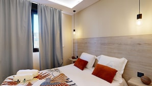 A modern hotel room with a large bed, a wooden headboard, and a skylight.