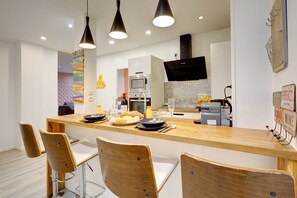 A modern kitchen with a wooden island, bar stools, pendant lighting, a microwave, and a built-in oven. - TBS 149 - Spacious, air-conditioned Apt in Paris 2 (Paris)