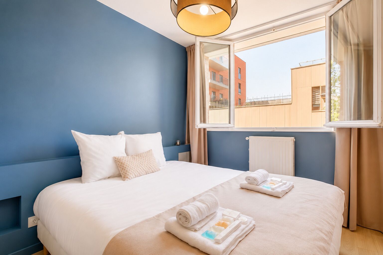 Een hotelkamer met een groot bed, een raam met uitzicht op gebouwen en een radiator.
