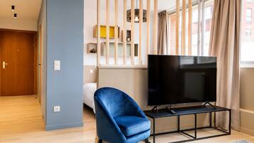 Een moderne woonkamer met een televisie, een blauwe stoel en een houten vloer.