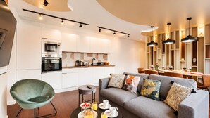 A modern living room with a grey sofa, a round coffee table, and a green armchair. - TBS 87 - Fabulous apartment in Paris (Paris)