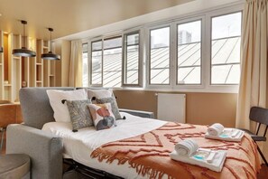 A hotel room with a bed, a chair, a table, a window, and a radiator. - TBS 87 - Fabulous apartment in Paris (Paris)
