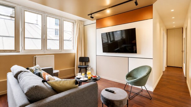 A modern living room with a sofa, a television, and a dining area with a table set for breakfast. - TBS 87 - Fabulous apartment in Paris (Paris)