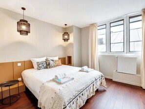 A hotel room with a bed, bedside tables, a window with curtains, and a radiator. - TBS 87 - Fabulous apartment in Paris (Paris)