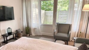 A bedroom with a large bed, a TV mounted on the wall, a chair, and a small table. - Compact and comfortable, Kompakt und Komfortabel (Bad Rothenfelde)