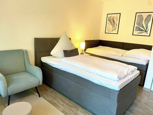 A hotel room with a single bed, a sofa, and two framed artworks on the wall. - Compact and comfortable, Kompakt und Komfortabel (Bad Rothenfelde)