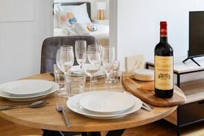 A dining table set with plates, glasses, and a bottle of Biaissac Bordeaux wine. - TheBlueStay 238- Beautiful Apartment in Paris 17 (Paris)