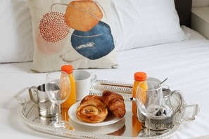 A breakfast tray with croissants, juice, and a teapot on a bed with a pillow. - TheBlueStay 238- Beautiful Apartment in Paris 17 (Paris)