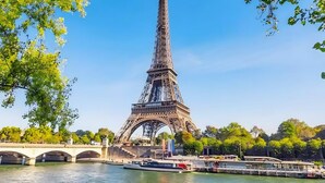 La Tour Eiffel, avec une rivière et un pont au premier plan.