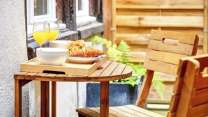 Una mesa de madera con un cuenco, dos vasos de jugo de naranja y un croissant.