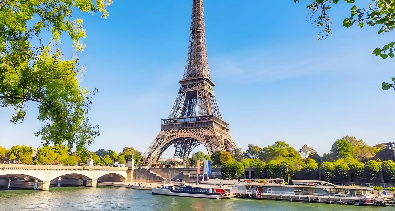 La Tour Eiffel, avec une rivière et un pont au premier plan.