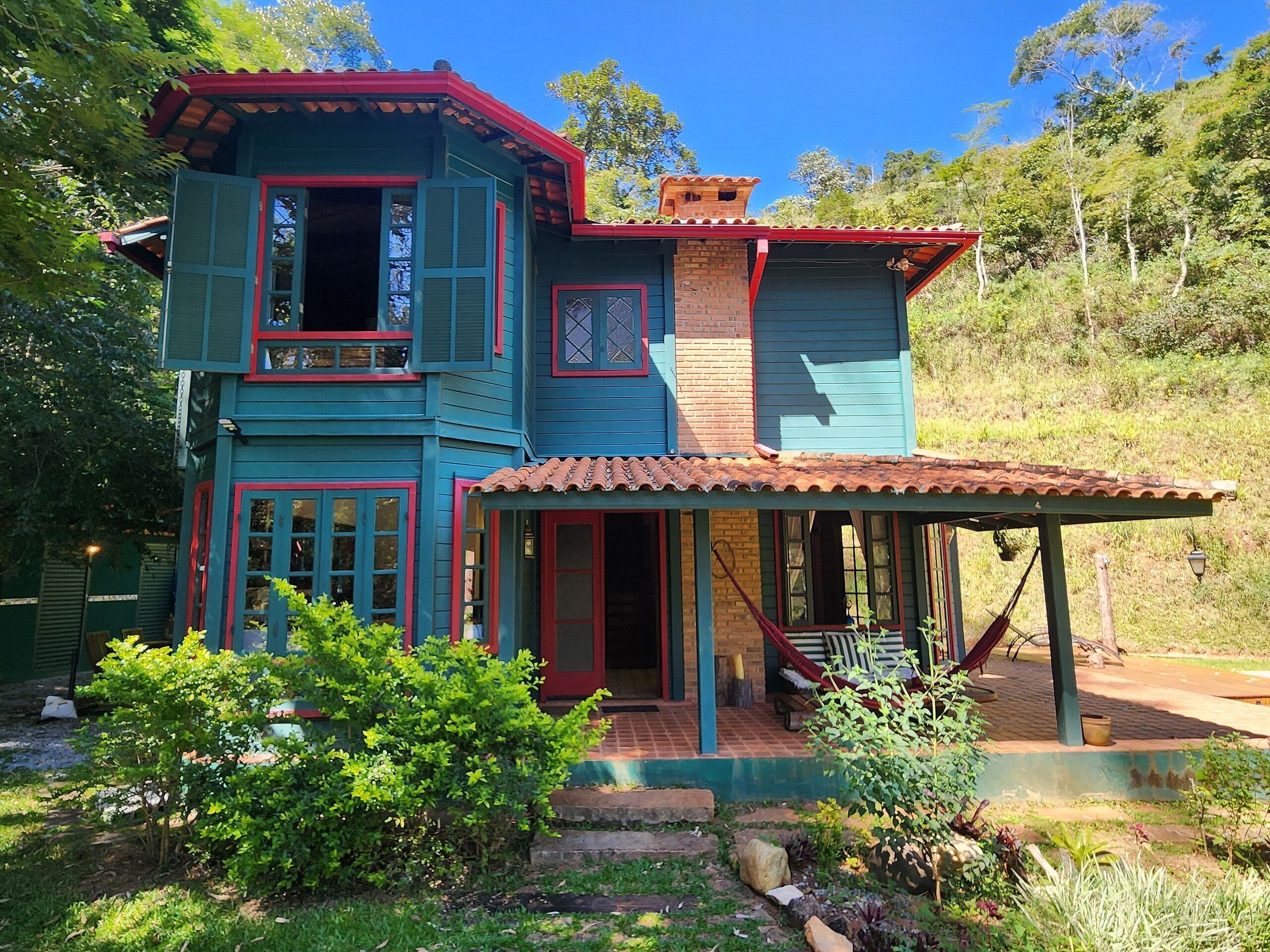 A two-story house with a covered porch and a hammock.