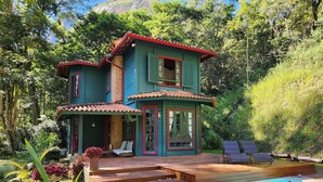 Una casa de dos pisos con piscina, rodeada de abundante vegetación.