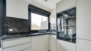 Une cuisine moderne dotée d’un plan de travail en marbre noir, de meubles blancs et d’un four encastré.