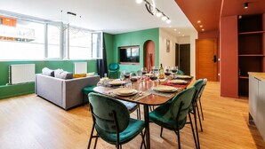 A modern living space with a dining area set for a meal, a sofa, and a television in the background. - TBS 88 - Elegant and modern apartment in Paris (Paris)