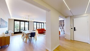 Un salon moderne avec un coin repas, de grandes fenêtres et un canapé rouge.