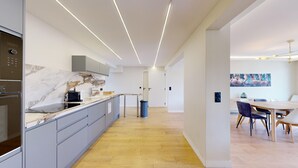 Une cuisine moderne avec des plans de travail en marbre, des meubles de couleur grise et un four encastré.