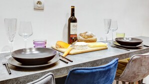 A dining table set with plates, a bottle of wine, cheese, bread, and glasses. - Cosy apartment near Opéra Garnier - Suite 222 (Paris)