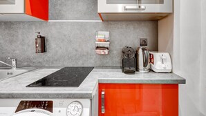 A kitchen with a built-in induction cooktop, a coffee maker, a kettle, and a toaster. - Cosy apartment near Opéra Garnier - Suite 222 (Paris)
