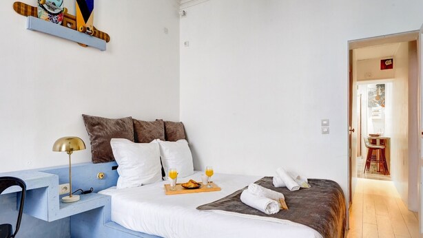 A modern bedroom with a bed, bedside table, lamp, and a breakfast tray with orange juice. - Cosy apartment near Opéra Garnier - Suite 222 (Paris)