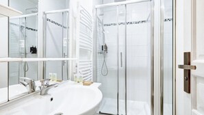 A modern bathroom with a large white sink, a glass shower enclosure, and a mirrored vanity. - Cosy apartment near Opéra Garnier - Suite 222 (Paris)