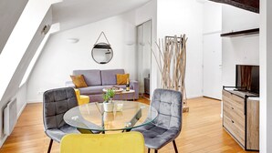 A modern loft apartment with a sloped ceiling, a glass dining table, a sofa, and a TV. - TBS 239 - Nice apartment in Moulin Rouge area (Paris)