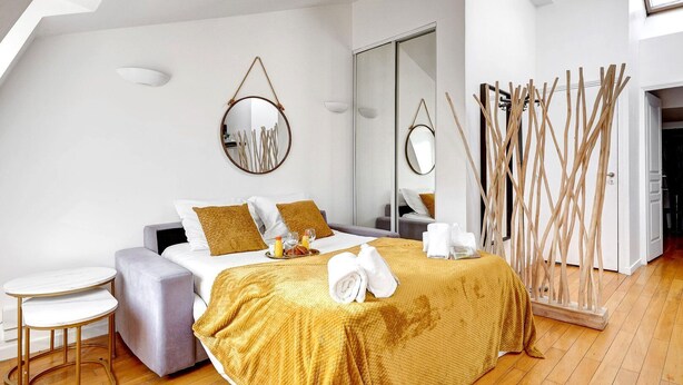 A modern bedroom with a bed, a small round table, and a mirror on the wall. - TBS 239 - Nice apartment in Moulin Rouge area (Paris)