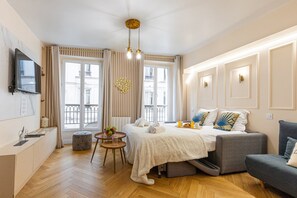 Et moderne hotelværelse med seng, sofa, lille bord og fjernsyn.